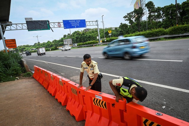 Dua petugas menata pembatas jalan saat penutupan akses tol ke arah Stasiun Kereta Cepat Whoosh Halim di Jalan Tol Jakarta-Cikampek KM 00+850 A, Jakarta, Minggu (18/2/2024). Foto: Erlangga Bregas Prakoso/Antara Foto