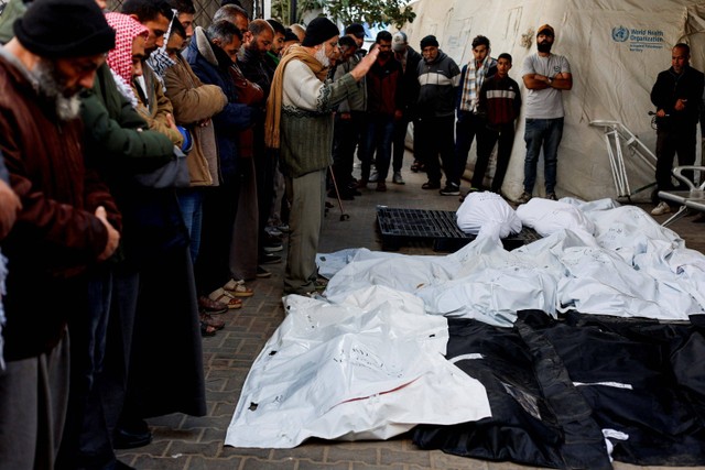 Para pelayat berdoa di samping jenazah warga Palestina yang tewas dalam serangan Israel di Rafah, Minggu (18/2/2024). Foto: Mohammed Salem/Reuters