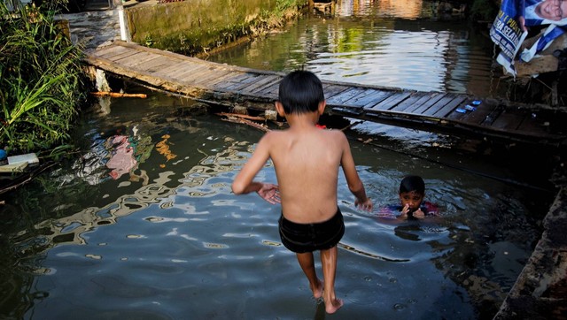 Hiburan kaum urban yang memanfaatkan anak sungai unutk mandi di tengah ancaman banjir saat musil hujan di Palembang, Sabtu (24/2) Foto: ary priyqnto/urban id