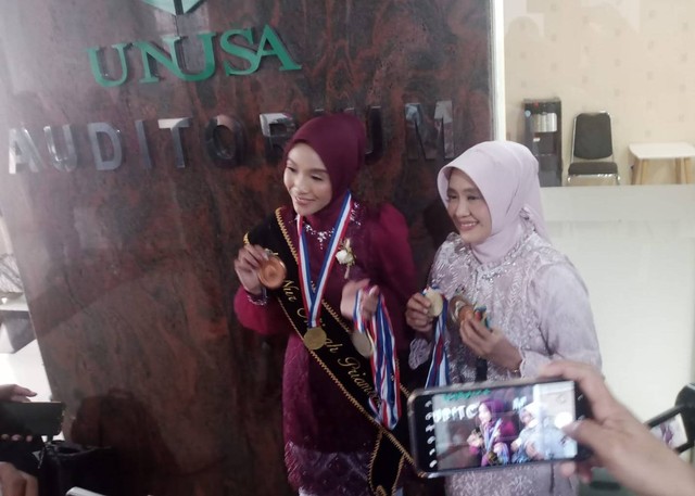 Alma (kebaya merah) menunjukkan koleksi medalinya sebagai atlet ski air. Foto: Masruroh/Basra