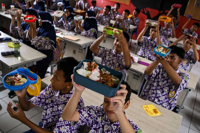 Sejumlah siswa menunjukkan makanan gratis saat simulasi program makan siang gratis di SMP Negeri 2 Curug, Kabupaten Tangerang, Banten, Kamis (29/2/2024). Foto: Sulthony Hasanuddin/Antara Foto