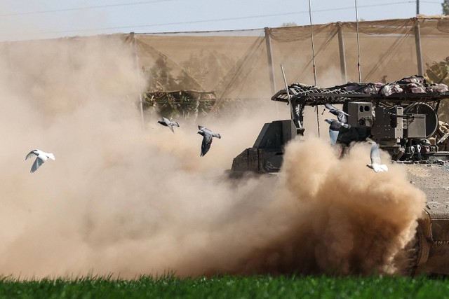 Sejumlah burung merpati terbang menghindari tank Israel saat pasukan kembali ke posisi di perbatasan Jalur Gaza pada 29 Februari 2024. Foto: Jack Guez / AFP