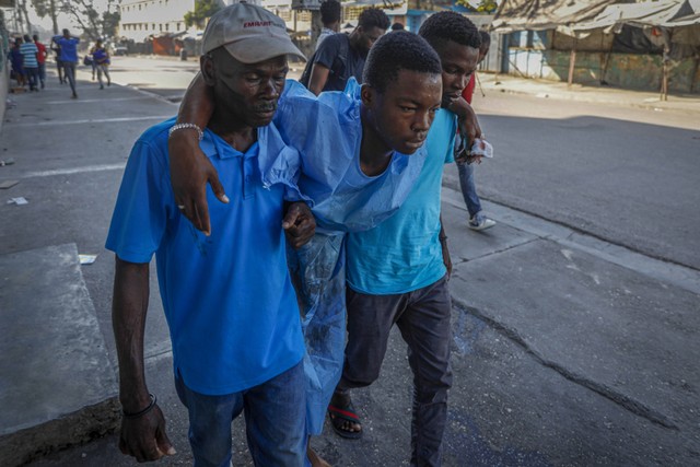 Para pria membantu mengevakuasi seorang pria dari Rumah Sakit Umum selama kekerasan geng di Port-au-Prince, Haiti, Kamis, 29 Februari 2024. Foto: AP/Odelyn Joseph