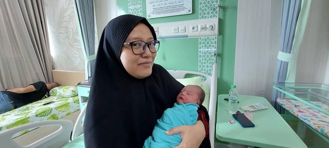 Vahruria saat menimang bayi Sarah yang lahir di momen Kabisat, Kamis (29/2) kemarin. Foto: Istimewa