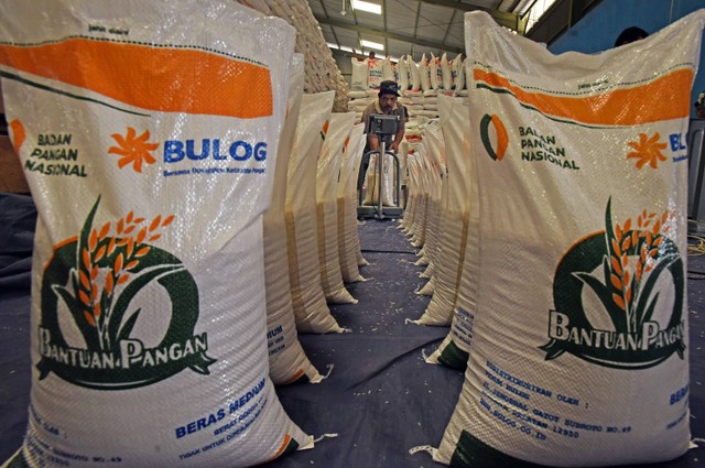 Pekerja menjahit karung berisi beras paket bantuan sosial pangan ukuran 10 kilogram di gudang Bulog Serang, Banten, Jumat (1/3/2024). Foto: ANTARA FOTO/Asep Fathulrahman