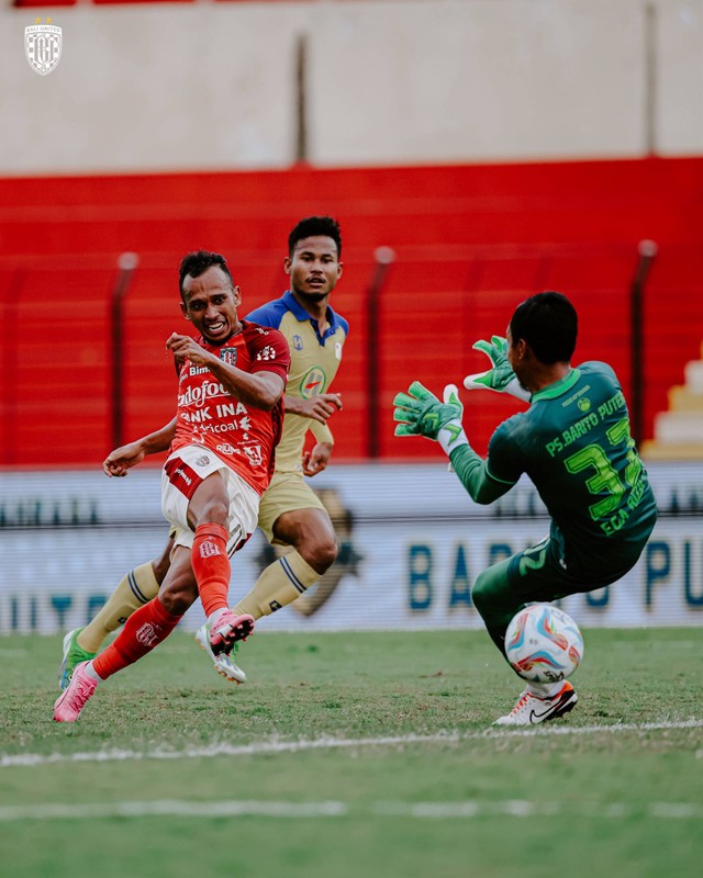 Irfan Jaya lepaskan tendangan di hadapan Ega Rizky saat laga Barito Putera vs Bali United dalam pekan ke-27 Liga 1 2023/24 di Stadion Sultan Agung, Bantul, pada Senin (4/3). Foto: X @BaliUtd