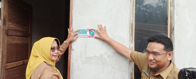 Bupati Mempawah Erlina menempel stiker secara simbolis menyerahkan hasil program perbaikan RTLH di Pulau Pedalaman. Foto: M. Zain/Hi!Pontianak