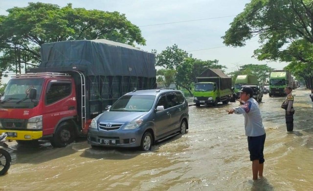 Petugas kepolisian saat mengatur lalu lintas di Jalur Pantura Cirebon Timur yang terendam banjir, Rabu (6/3). Foto: Tarjoni/Ciremaitoday