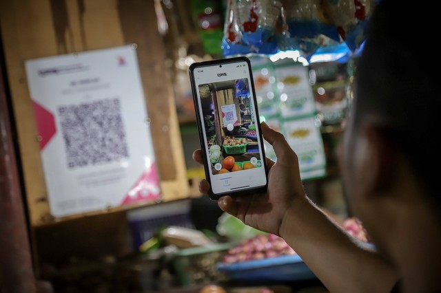 Pembeli menggunakan aplikasi Livin' Bank Mandiri untuk membayar dengan QRIS di pasar tradisional di Jakarta, Jumat (8/3/2024). Foto: Jamal Ramadhan/kumparan