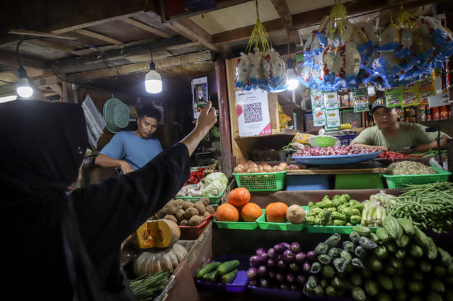 Pembeli menggunakan aplikasi Livin' Bank Mandiri untuk membayar dengan QRIS di pasar tradisional di Jakarta, Jumat (8/3/2024). Foto: Jamal Ramadhan/kumparan