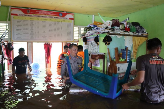 Anggota Polres Melawi membantu evakuasi barang-barang peralatan sekolah yang terendam banjir di SDN 26 Desa Sidomulyo. Foto: Dok. Polres Melawi