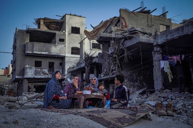 Keluarga Al-Naji Palestina berbuka puasa, di tengah reruntuhan rumah keluarga mereka, pada hari pertama bulan suci Ramadhan, di Deir el-Balah di Jalur Gaza tengah pada 11 Maret , 2024. Foto: AFP