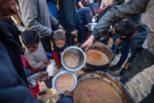 Pengungsi Palestina mengumpulkan makanan yang disumbangkan oleh sebuah badan amal sebelum berbuka puasa, pada hari pertama bulan suci Ramadhan, di Rafah di Jalur Gaza selatan pada 11 Maret 2024. Foto: Mohammed Abed / AFP