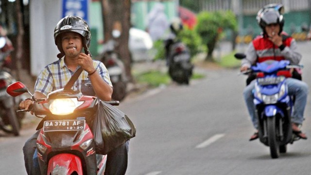 Sejumlah pengendara merokok sambil mengendarai sepeda motor, di Padang, Sumatera Barat. Foto: Antara/Muhammad Arif Pribadi