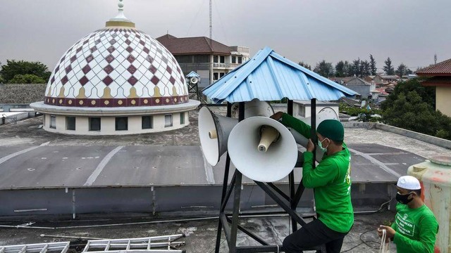 Foto ilustrasi: Dua pengurus masjid memeriksa pengeras suara luar pada salah satu tiang masjid di Jakarta.