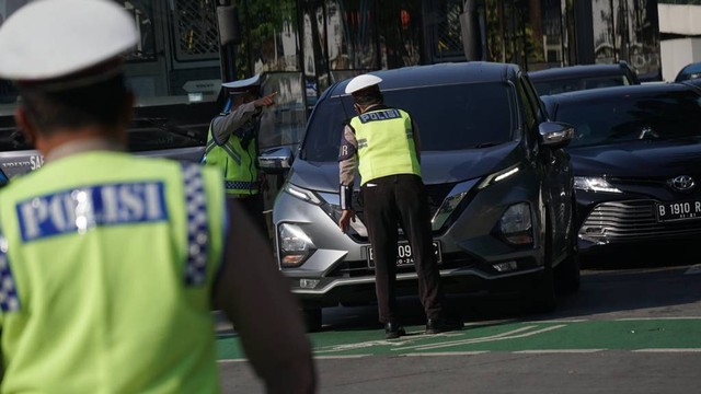 Polisi mengecek kendaraan saat penerapan Ganjil Genap di Bundaran Senayan, Jakarta, Kamis (12/8). Foto: Jamal Ramadhan/kumparan