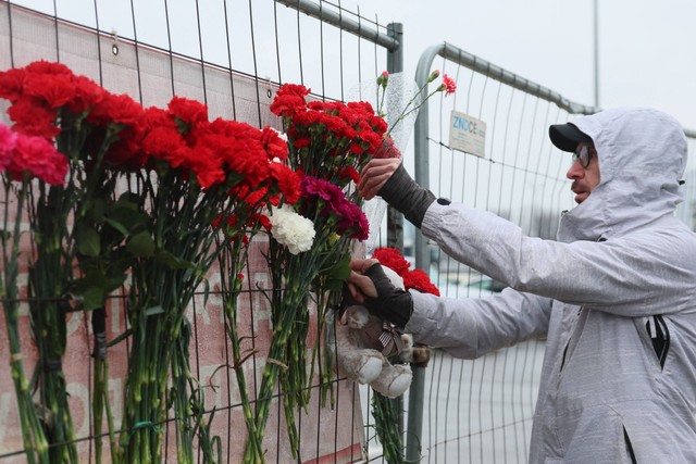 Warga meletakkan bunga di tugu peringatan darurat di depan Balai Kota Crocus, Sehari setelah serangan senjata di Krasnogorsk, luar Moskow, Sabtu (23/3/2024) Foto: STR/AFP