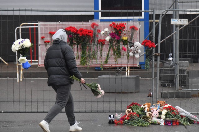 Warga meletakkan bunga di tugu peringatan darurat di depan Balai Kota Crocus, Sehari setelah serangan senjata di Krasnogorsk, luar Moskow, Sabtu (23/3/2024) Foto: STR/AFP