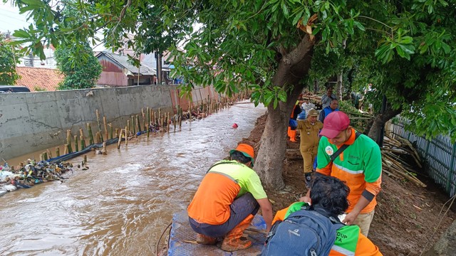 Petugas memperbaiki tanggul sungai yang jebol di Hek Kramat Jati, Jakarta, Senin (25/3/2024). Foto: Thomas Bosco/kumparan