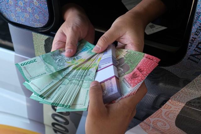 Warga menerima uang pecahan baru saat berlangsung layanan penukaran uang keliling di Kendari, Sulawesi Tenggara, Senin (25/3/2024). Foto: Andry Denisah/ANTARA FOTO