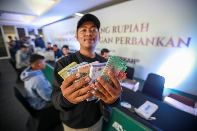 Warga menunjukkan uang Rupiah di Layanan Kas Keliling Terpadu pada momen Ramadan dan Idul Fitri 2024 di Istora Senayan, Jakarta, Kamis (28/3/2024). Foto: Aditia Noviansyah/kumparan