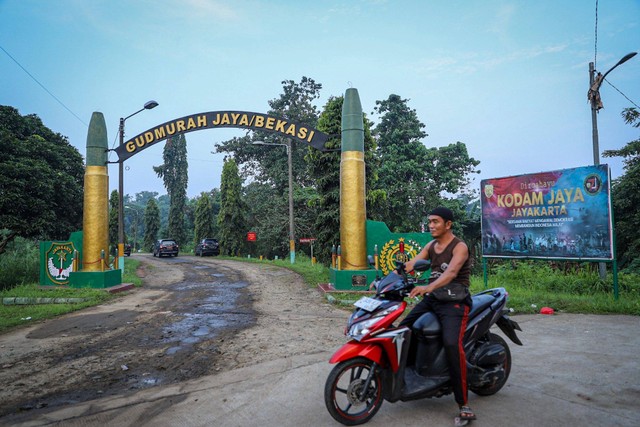 Warga melintas di depan gerbang Gudang amunisi Daerah (Gudmurah) Jaya/Bekasi, Ciangsana, Kabupaten Bogor, Jawa Barat, Minggu (30/3/2024). Foto: Iqbal Firdaus/kumparan