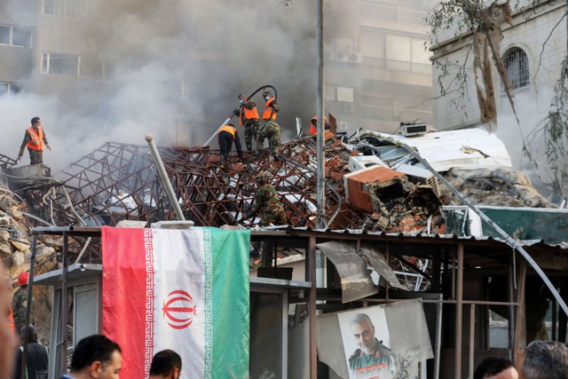 Personel darurat dan keamanan mencari puing-puing di lokasi serangan yang menghantam gedung yang merupakan bagian dari kedutaan Iran di Damaskus, Suriah, pada Senin (1/4/2024). Foto: Louai Beshara / AFP