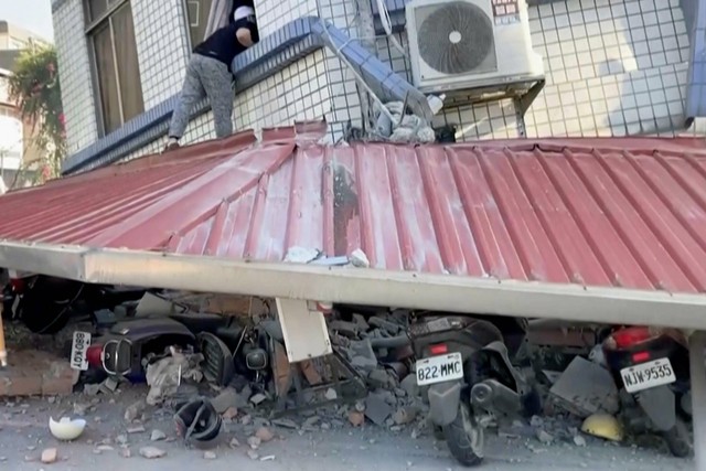Dalam gambar yang diambil dari cuplikan video yang ditayangkan TVBS, seorang pria memeriksa sebagian bangunan yang runtuh di Hualien, Taiwan timur pada Rabu, (3/4/2024) Foto: TVBS/AP