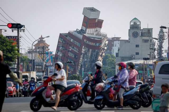 Orang-orang mengendarai sepeda motor di dekat lokasi bangunan runtuh akibat gempa, di Hualien, Taiwan (4/4/2024). Foto: REUTERS/Carlos Garcia Rawlins