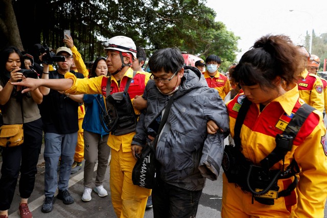 Seorang pria dibantu oleh personel darurat setelah diselamatkan, pasca gempa, di Hualien, Taiwan, Jumat (5/4/2024). Foto: Tyrone Siu/REUTERS 