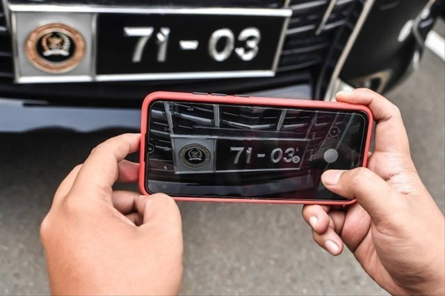 Seorang petugas mengambil gambar logo pada kendaraan dengan pelat nomor khusus anggota DPR yang terparkir di Kompleks Parlemen, Senayan, Jakarta, Senin (24/5). Foto: Muhammad Adimaja/ANTARA FOTO