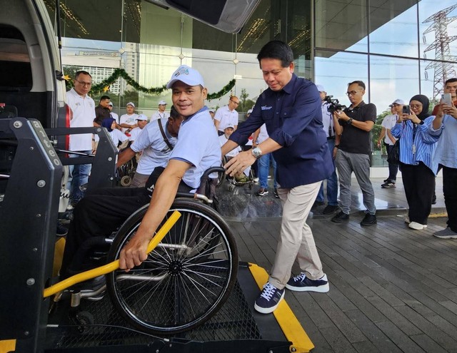 Direktur Utama BSI, Hery Gunardi (kanan), membantu mendorong pemudik naik ke mobil khusus disabilitas saat pelepasan peserta Mudik Asyik Bersama BUMN dan BSI 2024 di Kantor Pusat BSI, Gedung The Tower Jakarta, Jumat (5/4). Foto: dok. BSI