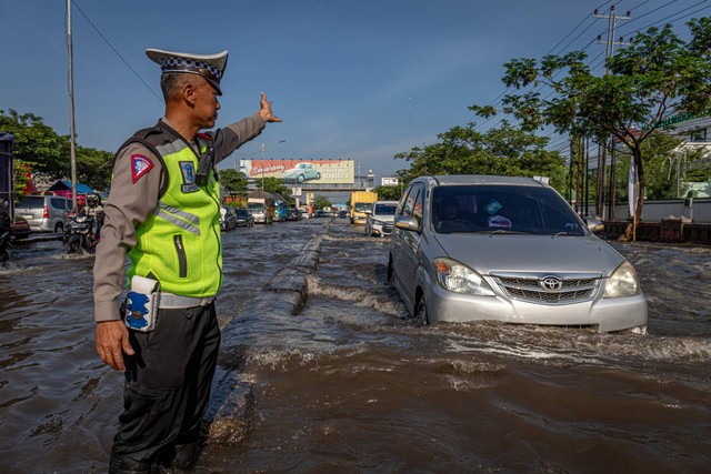 Petugas kepolisian mengatur arus lalu lintas yang tersendat karena banjir menggenangi jalur utama pantura Semarang-Surabaya di Jalan Kaligawe Raya, Kota Semarang, Jawa Tengah, Sabtu (6/4/2024). Foto: Aji Styawan/ANTARA FOTO 