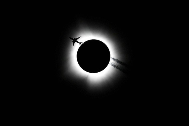 Sebuah pesawat melintas saat gerhana matahari total di Bloomington, Indiana, Amerika Serikat, Senin (8/4/2024). Foto: Bobby Goddin/USA Today Network via REUTERS