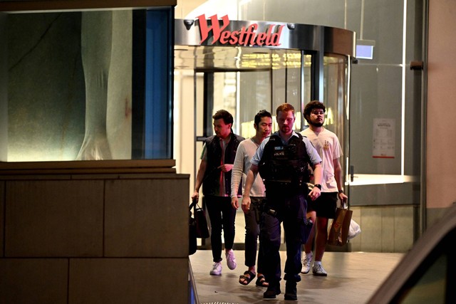Masyarakat dikawal oleh petugas polisi NSW dari dalam Westfield Bondi Junction setelah beberapa orang ditikam di dalam pusat perbelanjaan pinggiran timur di Sydney, Australia, Sabtu (13/4/2024). Foto: AAP Image/Bianca De Marchi via REUTERS