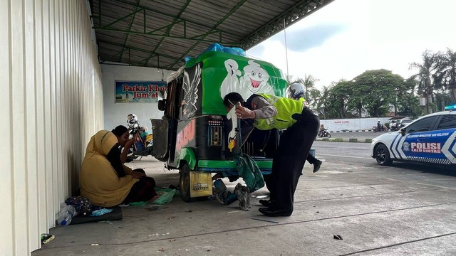 Anggota Polres Mojokerto melakukan pertolongan pertama terhadap kendaraan bajaj pemudik Jakarta-Banyuwangi yang mogok di Trowulan.  Foto: Nana/mili.id