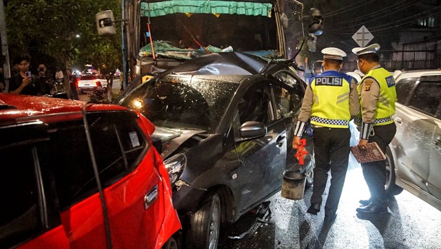 Dua petugas kepolisian yang mengecek salah satu unit kendaraan yang ringsek akibat kecelakaan beruntun yang terjadi selasa malam, Rabu (17/4) Foto: ary priyanto/urban id