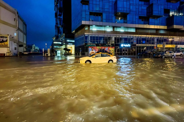 Sebuah taksi melewati jalan yang banjir setelah hujan lebat di Dubai (17/4/2024) Foto: GIUSEPPE CACACE / AFP