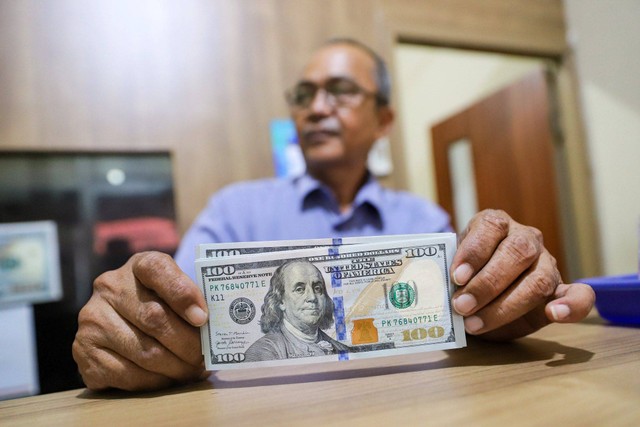 Petugas menujukkan pecahan mata uang Dolar di salah satu gerai penukaran mata uang di kawasan Kemang, Jakarta, Rabu (17/4/2024). Foto: Iqbal Firdaus/kumparan