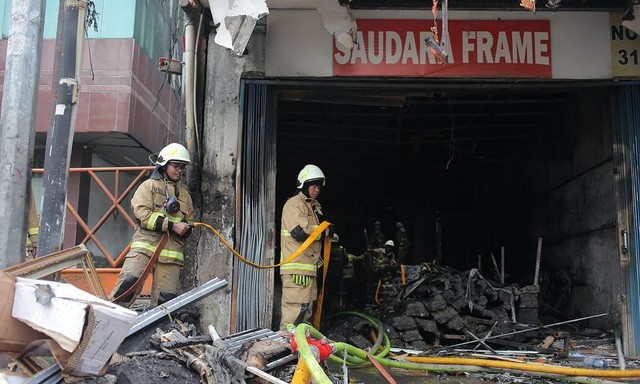Petugas pemadam kebakaran melakukan pendinginan ruko Saudara Frame dan Galery yang terbakar di Jalan Mampang Prapatan, Jakarta, Jumat (19/4/2024). Foto: Reno Esnir/Antara Foto