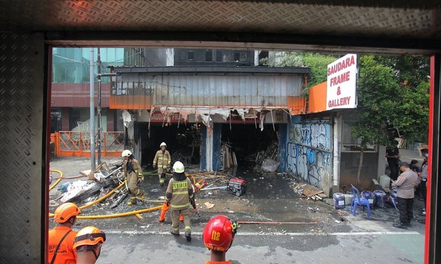 Petugas pemadam kebakaran melakukan pendinginan ruko Saudara Frame dan Galery yang terbakar di Jalan Mampang Prapatan, Jakarta, Jumat (19/4/2024). Foto: Reno Esnir/Antara Foto