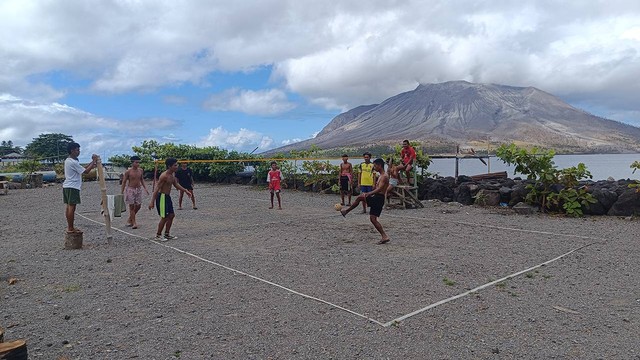 Sejumlah pemuda di Pulau Tagulandang asyik bermain sepak takraw dengan berlatar belakang Gunung Ruang, Minggu (21/4) pagi ini. (foto: febry kodongan/manadobacirita)