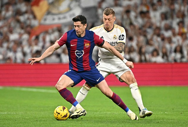 Duel Robert Lewandowski dengan Toni Kroos saat Real Madrid vs Barcelona dalam laga lanjutan Liga Spanyol 2023/24 di Estadio Santiago Bernabeu pada Senin (22/4) dini hari WIB. Foto: AFP/Javier Soriano