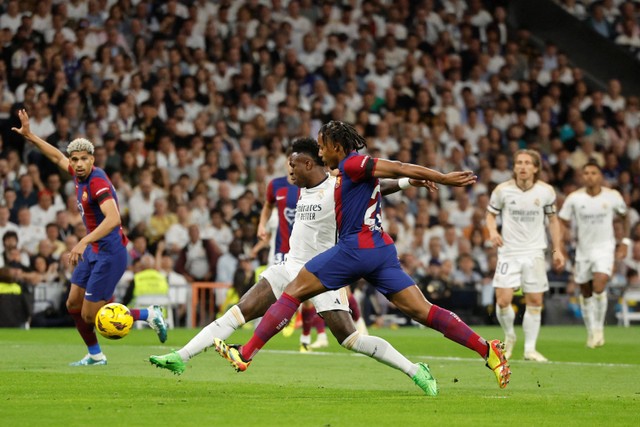 Pemain Real Madrid Vinicius Junior berebut bola dengan pemain FC Barcelona Jules Kounde pada pertandingan lanjutan Liga Spanyol di Stadion Santiago Bernabeu, Madrid, Spanyol, Minggu (21/4/2024). Foto: OSCAR DEL POZO / AFP