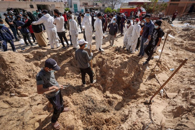 Petugas kesehatan Palestina menggali jenazah yang dikuburkan oleh pasukan Israel di kompleks rumah sakit Nasser di Khan Yunis di Jalur Gaza, Minggu (21/4/2024). Foto: AFP