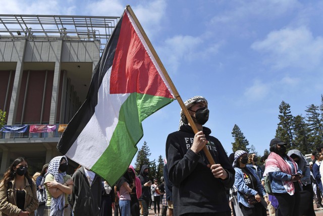 Seorang pengunjuk rasa Pro-Palestina memegang bendera Palestina saat berada di depan Sproul Hall saat melakukan protes di kampus UC Berkeley di Berkeley, California, pada Senin, 22 April 2024.  Foto: Jose Carlos Fajardo/Grup Berita Bay Area melalui AP