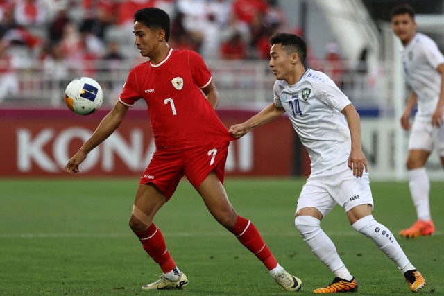 Pemain Timnas U-23 Indonesia Marselino Ferdinan berebut bola dengan pemain Timnas U-23 Uzbekistan Abbosbek Fayzullaev pada pertandingan semifinal Piala Asia U-23 di Stadion Abdullah Bin Khalifa, Doha, Qatar, Senin (29/4/2024). Foto: Karim Jaafar / AFP