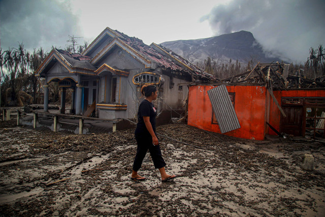 Warga berjalan di depan rumah yang rusak parah terdampak erupsi Gunung Ruang di Desa Laingpatehi Pulau Ruang, Kabupaten Kepulauan Sitaro, Sulawesi Utara, Jumat (3/5/2024). Foto: ANTARA FOTO/Andri Saputra