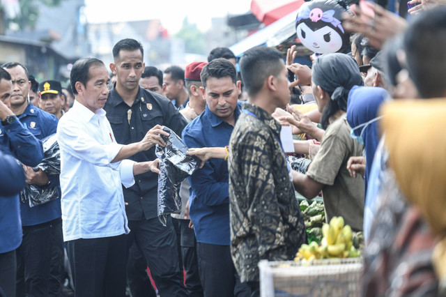 Presiden Joko Widodo (kiri) membagikan baju ke warga saat berkunjung ke Pasar Baru Karawang, Jawa Barat, Rabu (8/5/2024). Foto: Hafidz Mubarak/ANTARA FOTO