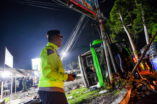 Petugas kepolisian berdiri di samping bangkai bus yang terlibat kecelakaan di Desa Palasari, Kecamatan Ciater, Kabupaten Subang, Jawa Barat, Sabtu (11/5/2024). Foto: Raisan Al Farisi/ANTARA FOTO